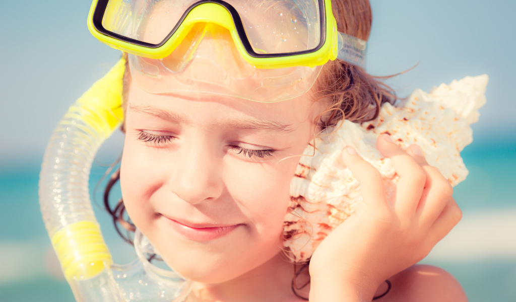 Маленькая девочка приложила ракушку к уху