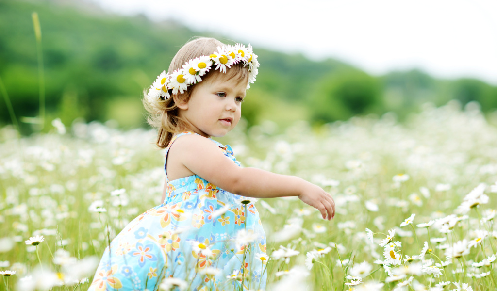 Маленькая девочка с венком на голове гуляет по полю с ромашками