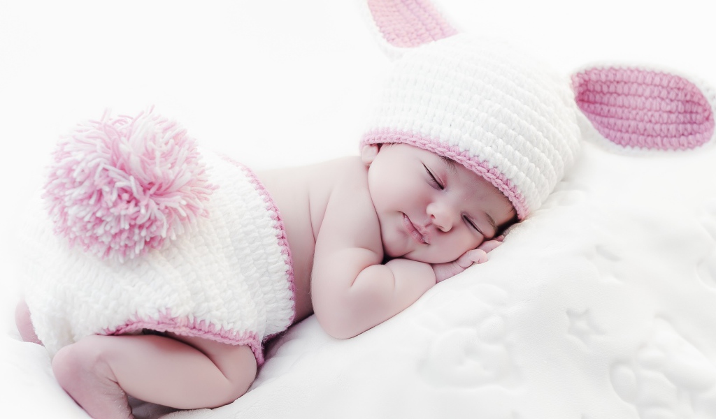 Маленький спящий ребенок в вязаном костюме зайчика