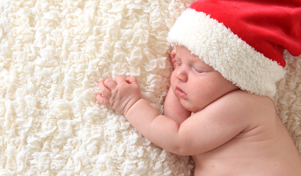 Маленький спящий ребенок в красном новогоднем колпаке