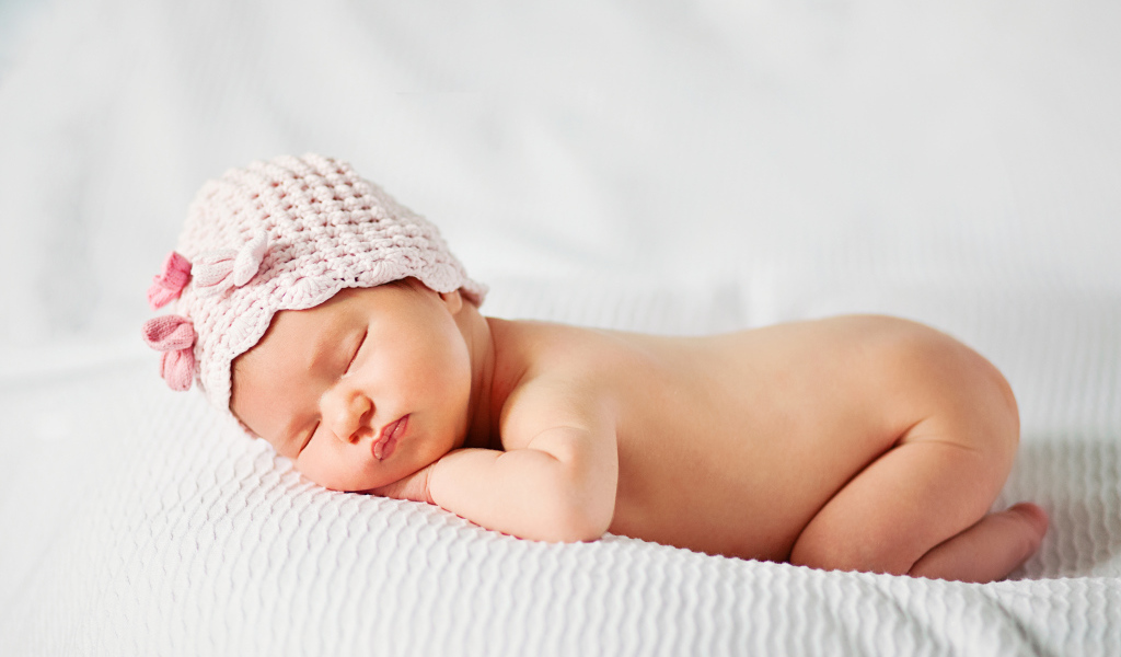 Спящий младенец девочка в розовой шапке