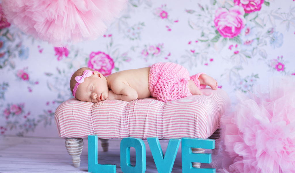 Спящий грудной ребенок в розовом костюме и надписью love
