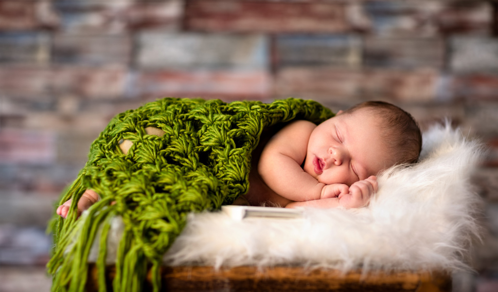 Спящий младенец под зеленым вязаным пледом