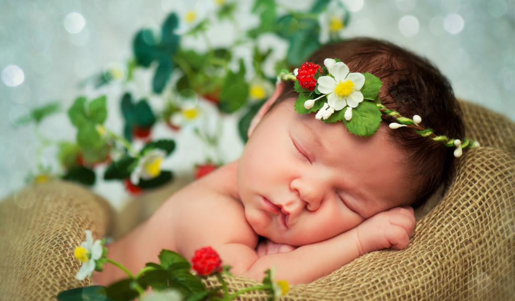 Спящий грудной ребенок с красивой повязкой на голове