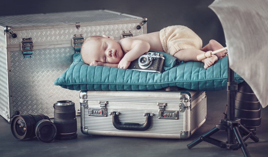 Спящий младенец с фотоаппаратом спит на чемодане