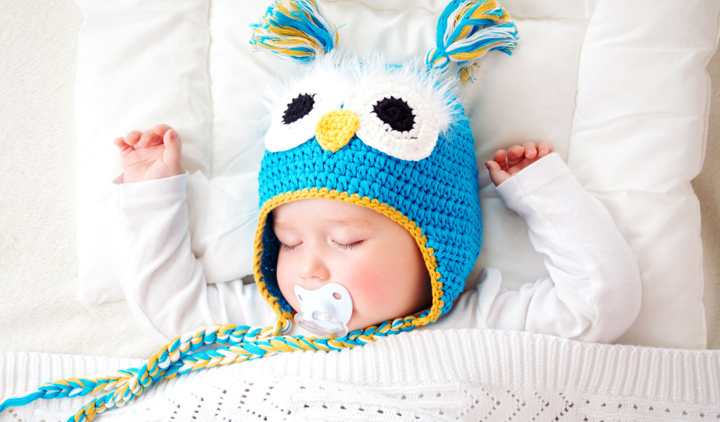 Спящий ребенок в забавной вязаной шапке