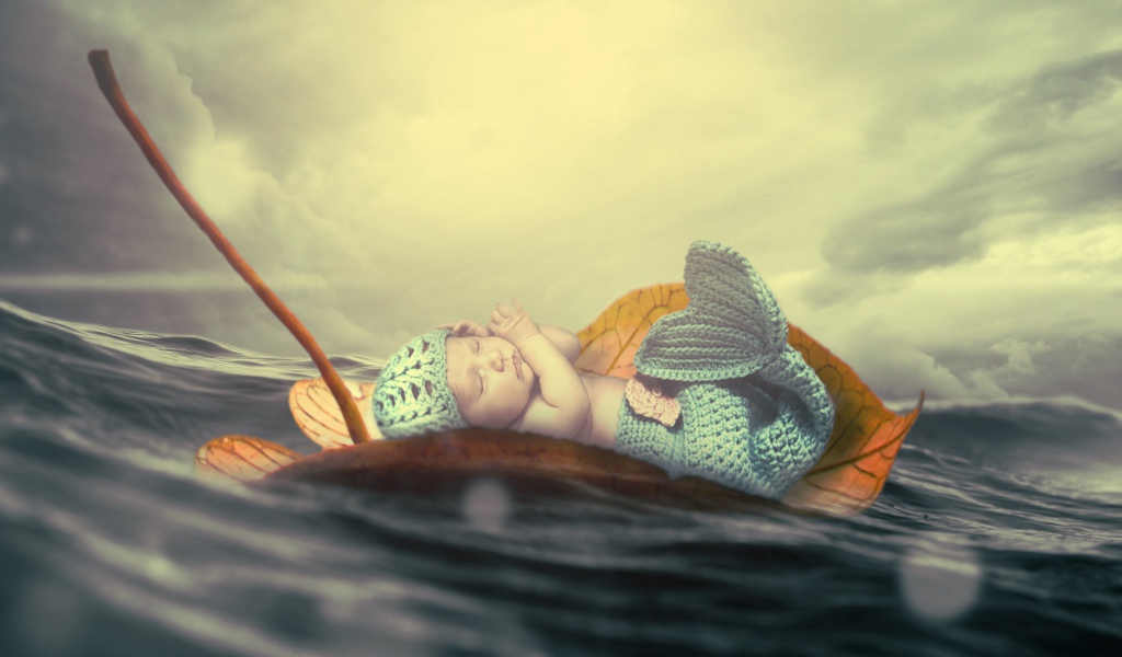 Маленький грудной ребенок в костюме русалки плывет на листе в океане