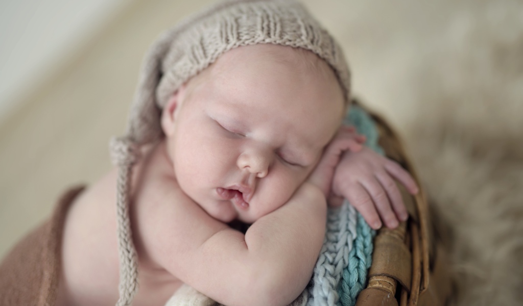 Маленький грудной ребенок спит в вязаной шапке