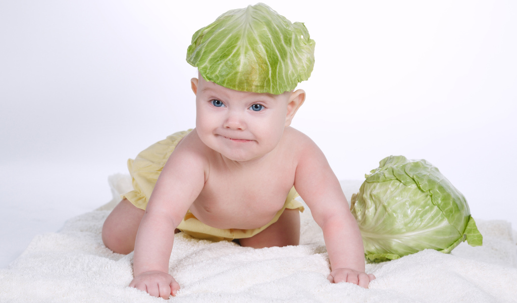 Маленький грудной ребенок с капустным листом на голове