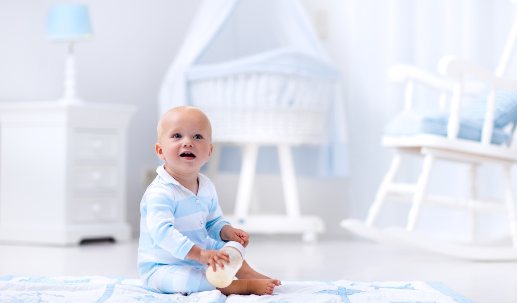 Маленький голубоглазый мальчик сидит на полу в комнате