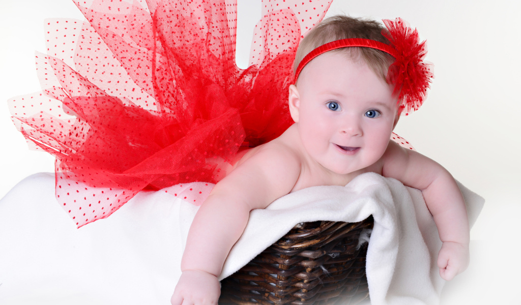 Маленькая голубоглазая девочка в красном красивом платье лежит в корзине