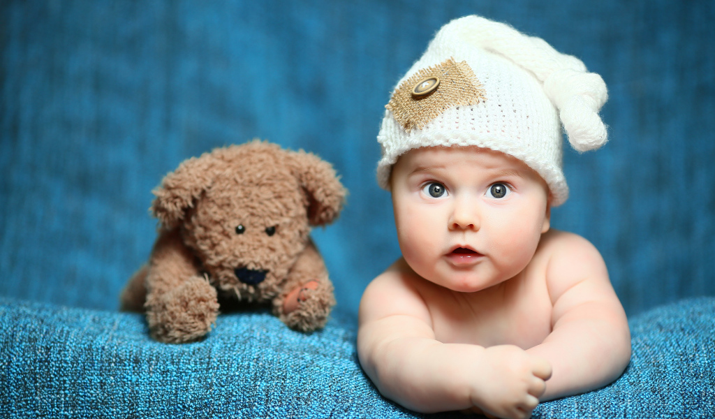 Маленький ребенок с красивой белой шапке с плюшевым медведем