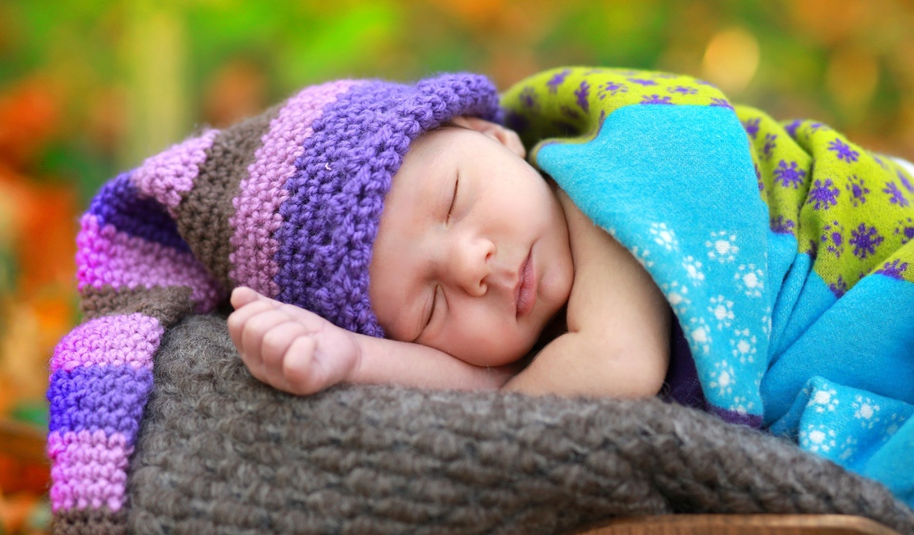Маленький спящий младенец в вязаной шапке 