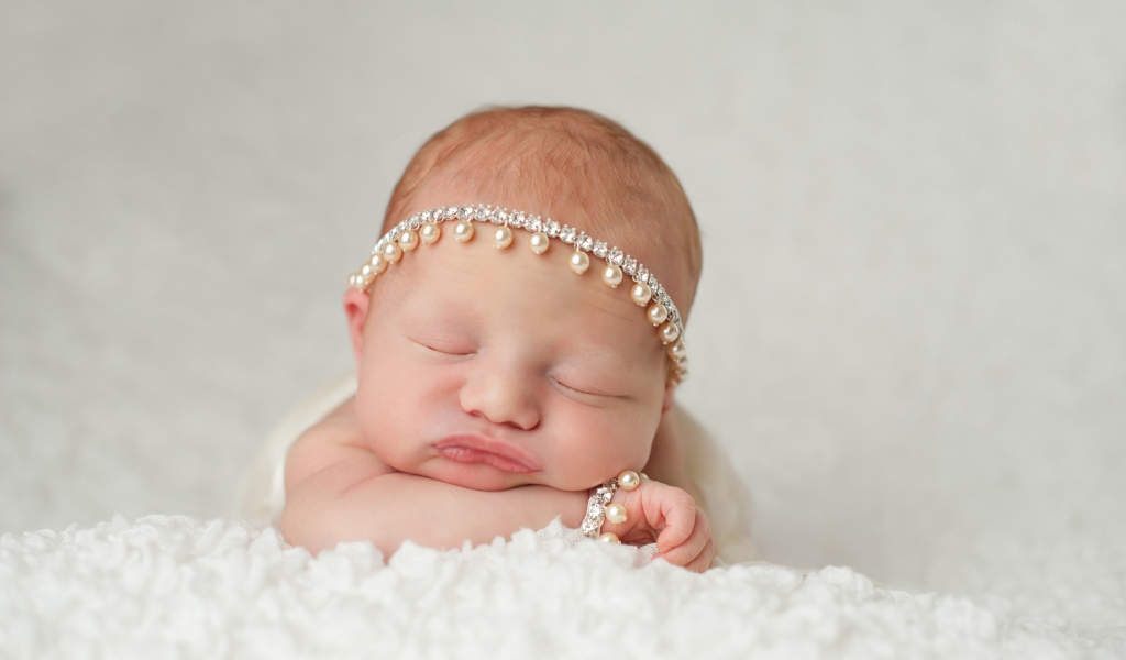 Маленький спящий грудной ребенок с красивым украшением на голове