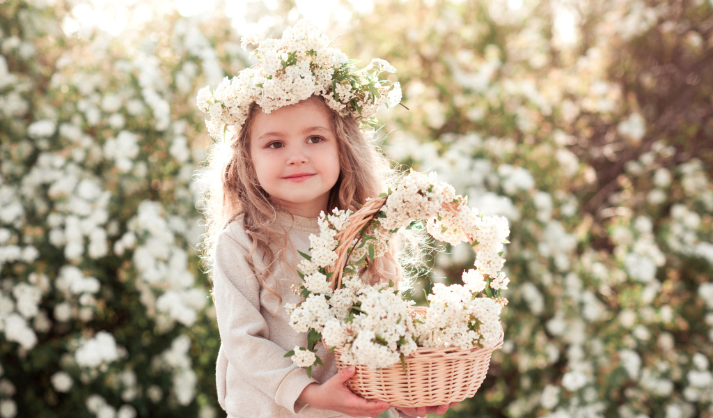 Милая маленькая девочка с венком на голове и корзиной белых цветов