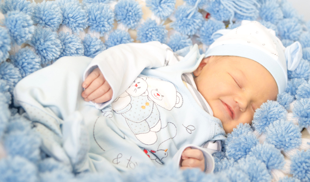 Младенец мальчик улыбается во сне