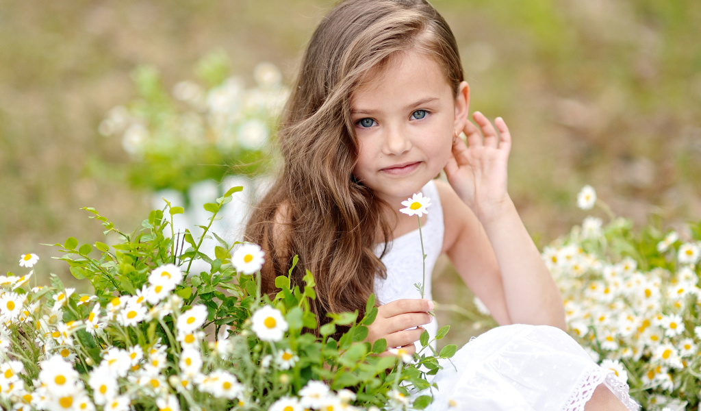 Красивая голубоглазая девочка с белой ромашкой в руке