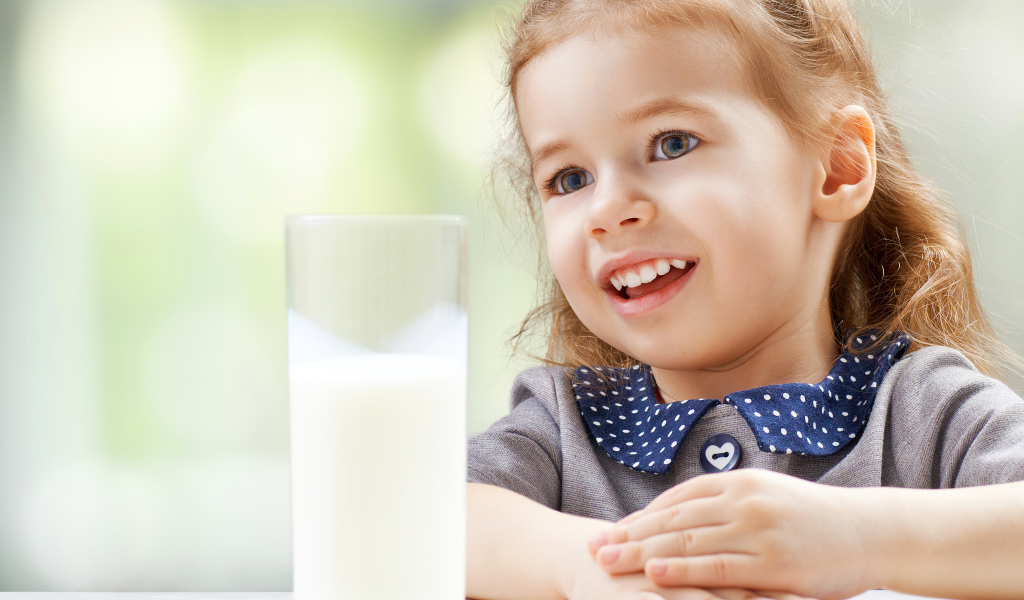 Красивая кареглазая девочка со стаканом молока