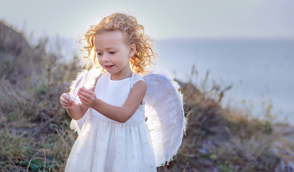 Красивая маленькая девочка в белом платье с крыльями ангела