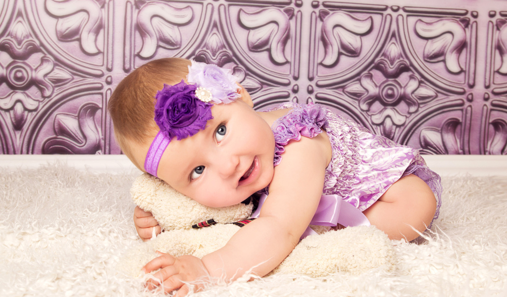 Красивая маленькая девочка в фиолетовом костюме с плюшевым мишкой