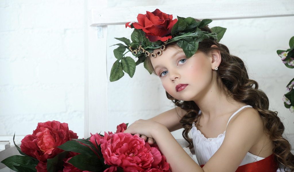 Красивая маленькая девочка с венком из роз на голове