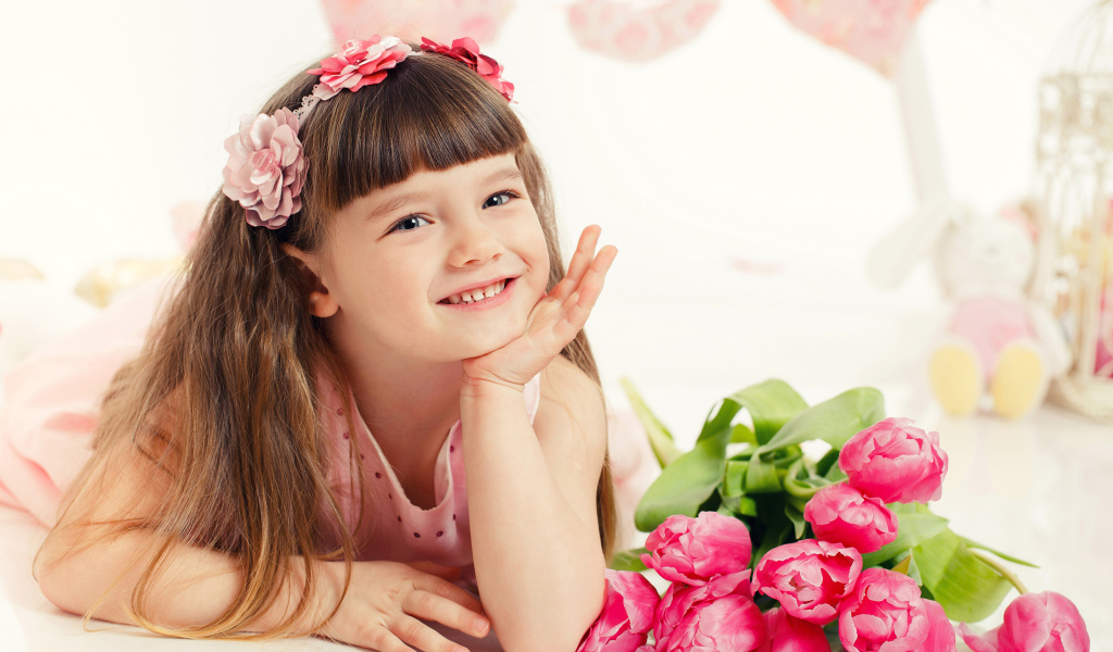 Красивая длинноволосая улыбающаяся девочка с букетом розовых тюльпанов