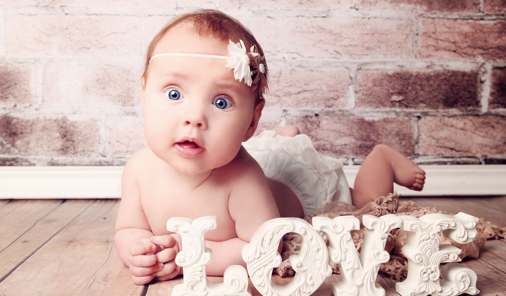 Грудной ребенок с надписью любовь на фоне кирпичной стены