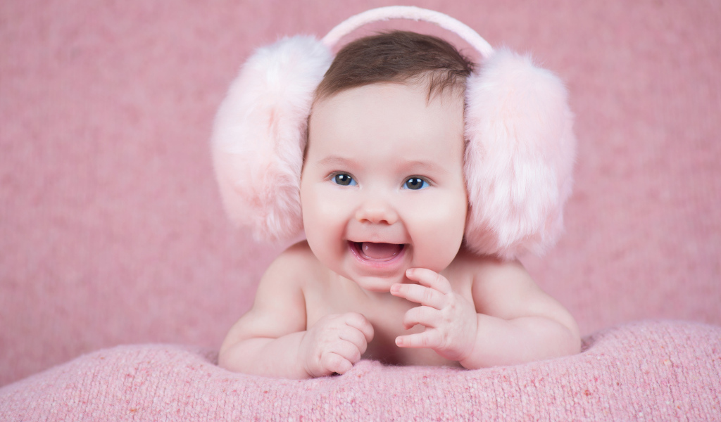 Милый улыбающийся младенец в больших розовых наушниках