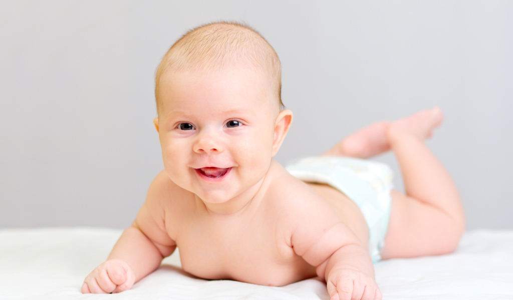 Милый улыбающийся ребенок на сером фоне