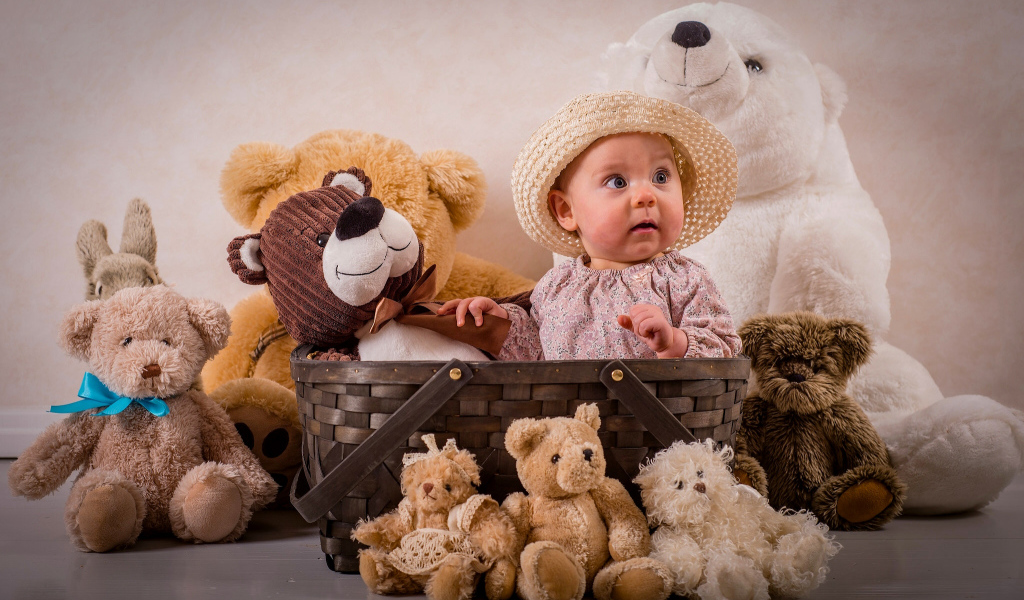 Забавный грудной ребенок в корзине с мягкими игрушками