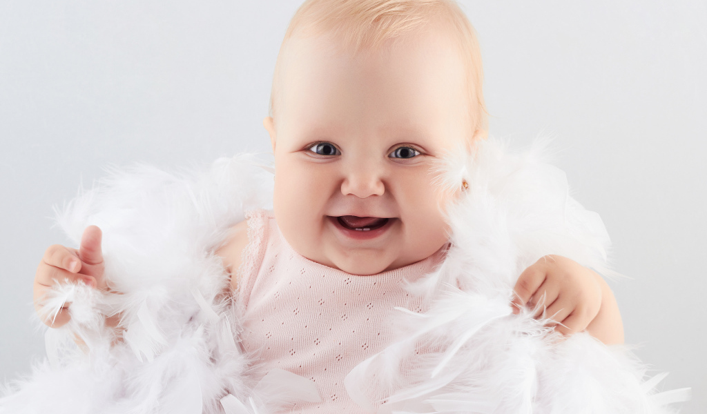 Забавная улыбающаяся маленькая девочка в белых перьях