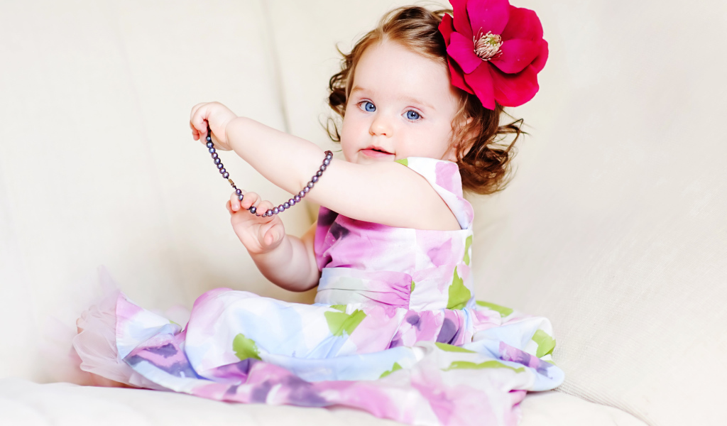 Маленькая голубоглазая девочка с красным цветком в волосах