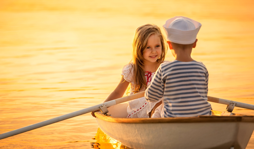 Маленькие мальчик и девочка плывут в лодке на закате солнца