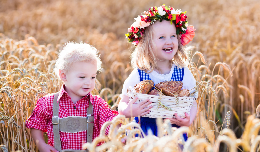 Маленькие мальчик и девочка на поле пшеницы с корзиной свежей выпечки
