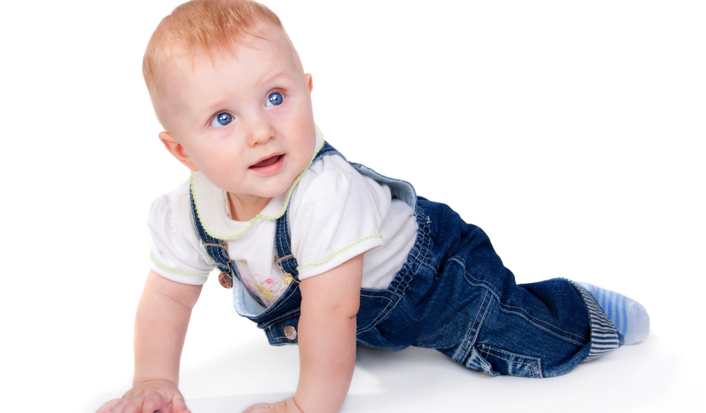 Маленький мальчик в синем комбинезоне на белом фоне