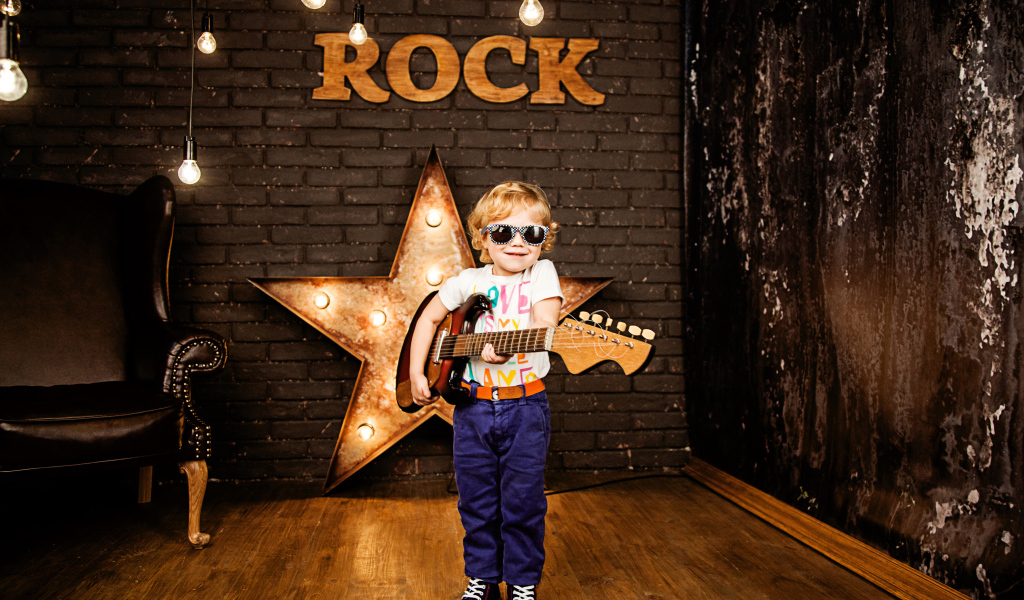 Маленький мальчик в модных очках с гитарой