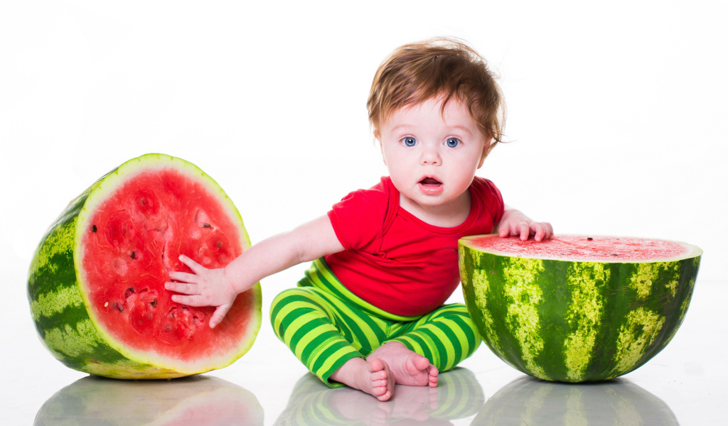 Маленький мальчик с половинами арбуза на белом фоне