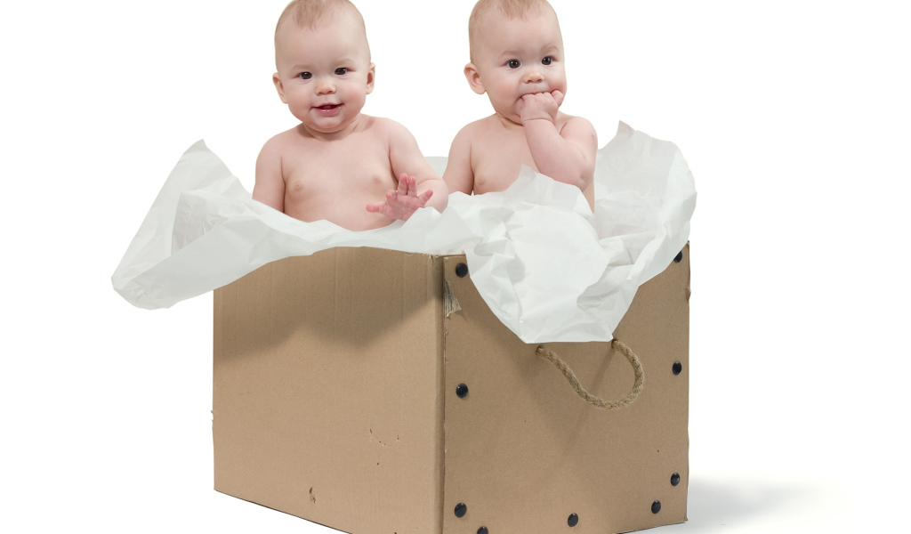 Маленькие дети сидят в картонной коробке с бумагой