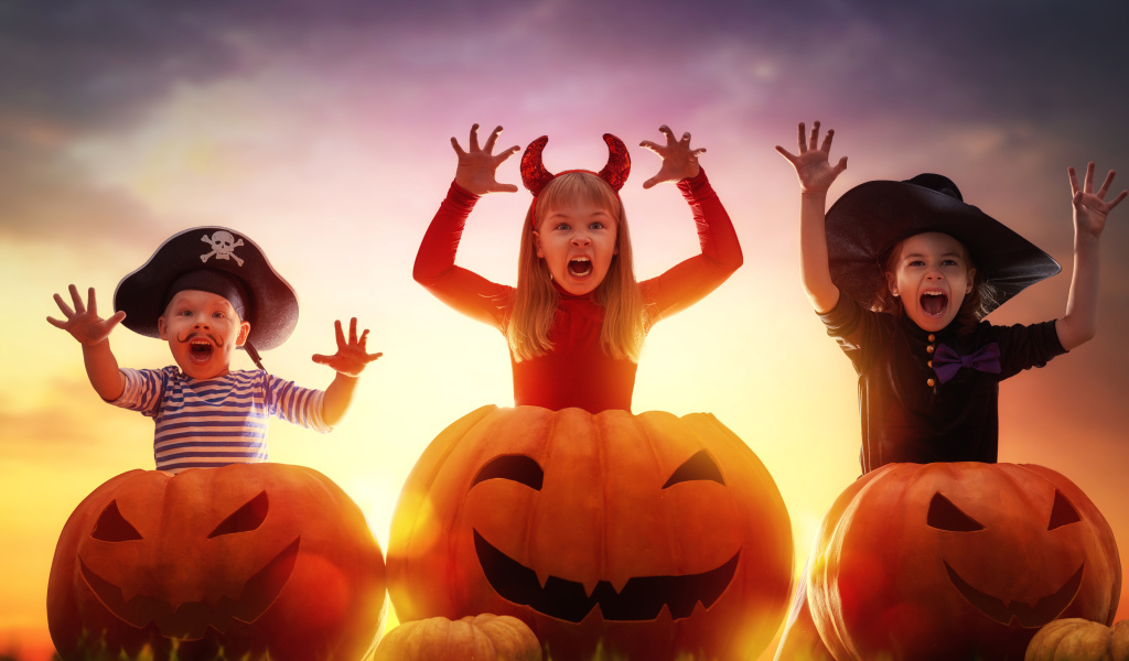 Маленькие дети в костюмах на Хэллоуин с большими тыквами