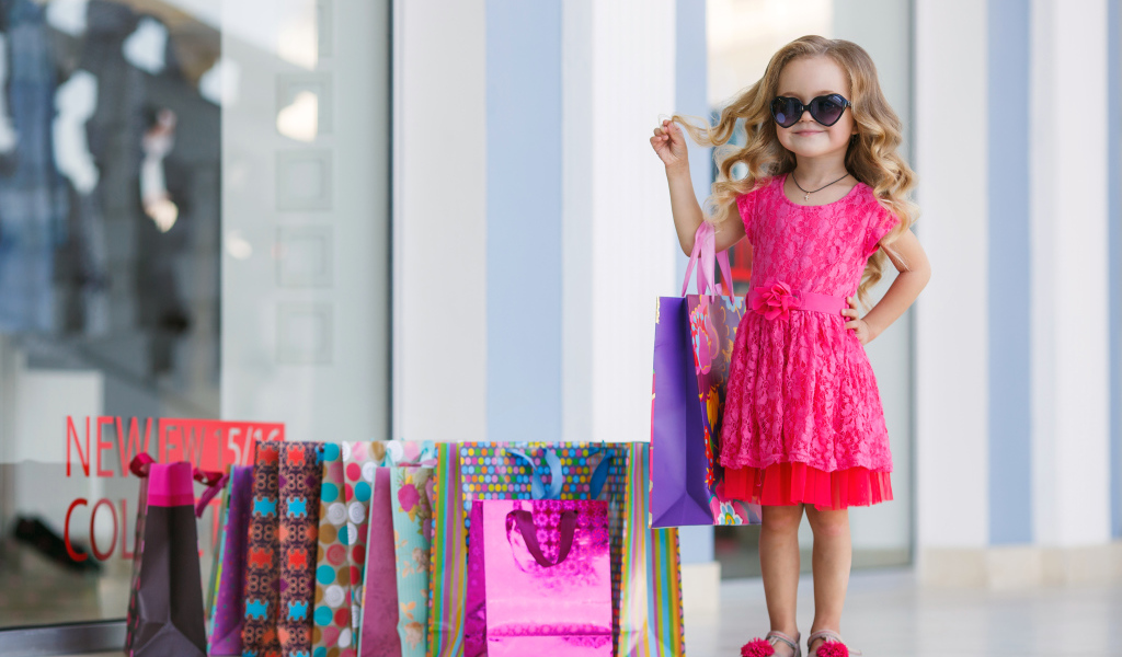 Маленькая модная девочка в красном платье с покупками