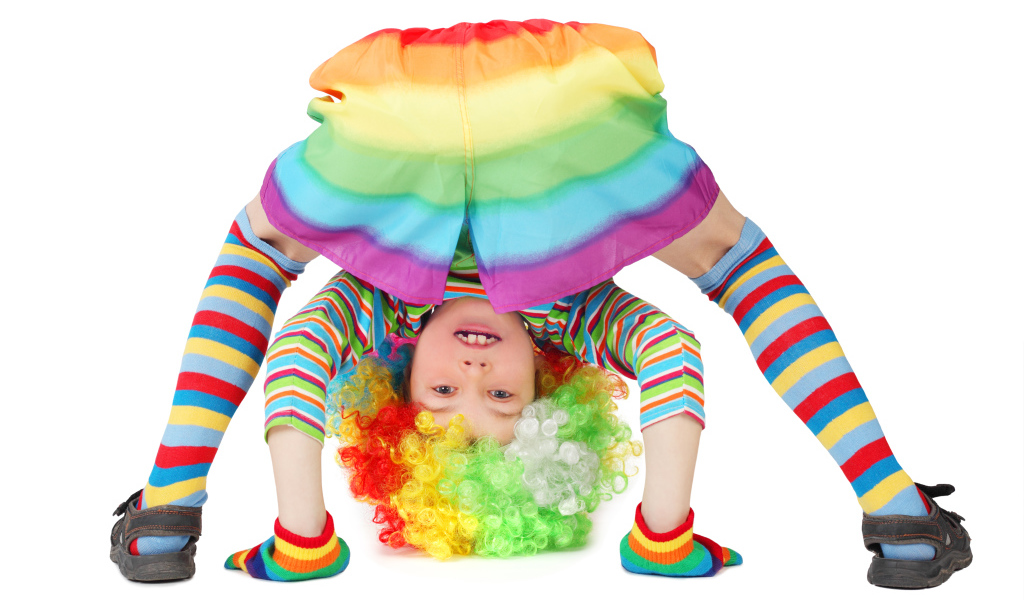 Маленькая смешная девочка в костюме клоуна на белом фоне