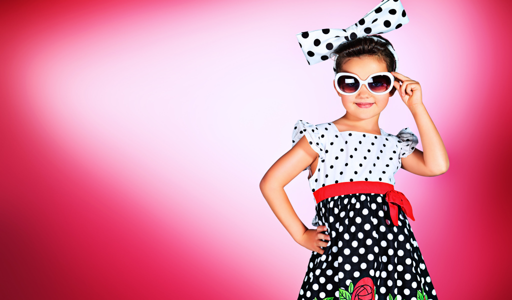 Маленькая девочка в красивом платье в горох на розовом фоне