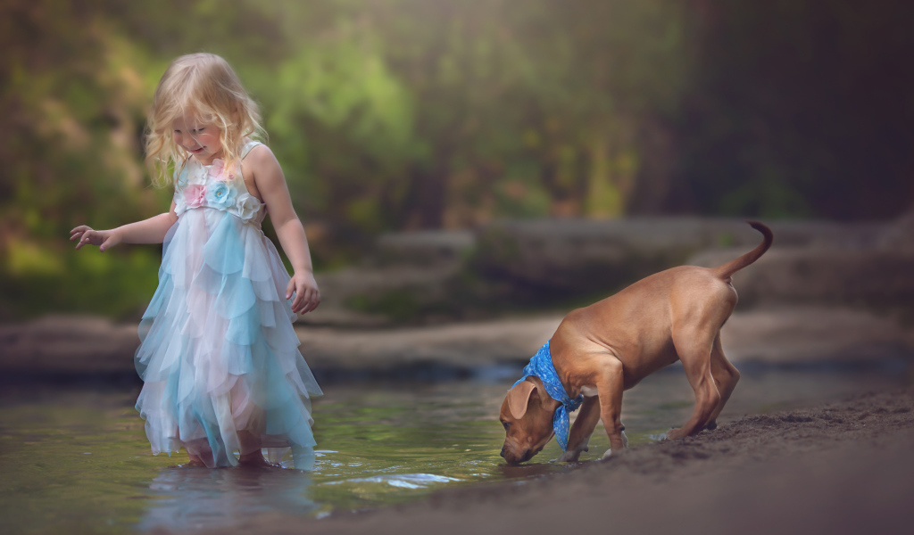 Маленькая девочка в красивом платье со щенком у ручья