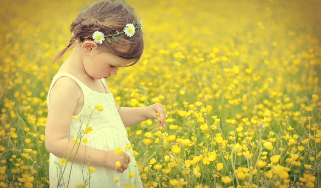 Маленькая девочка в белом платье на лугу с желтыми цветами