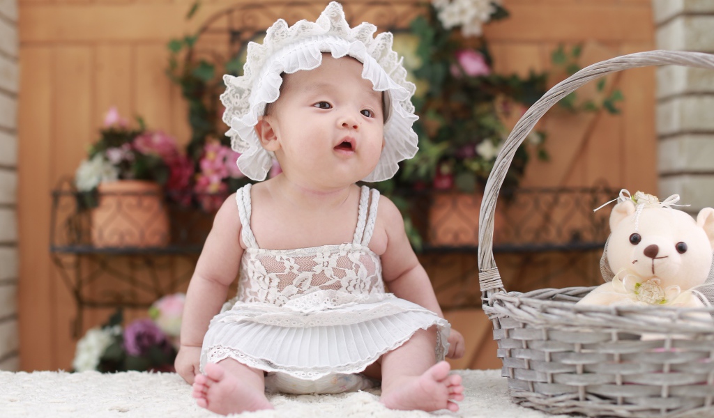 Маленькая девочка в белом платье с медвежонком в корзине