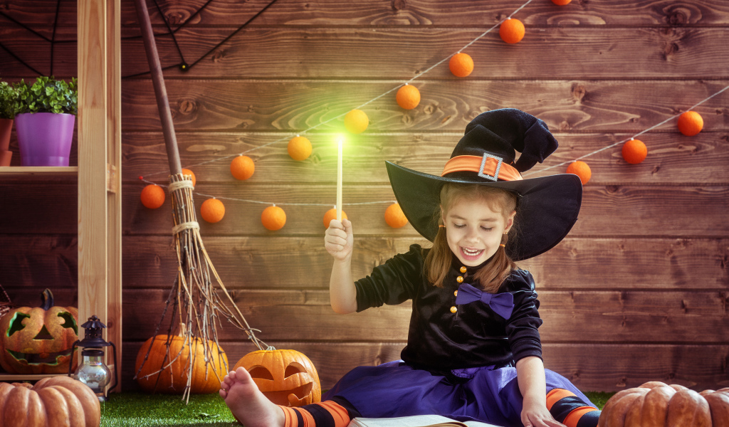 Маленькая девочка в костюме ведьмы с волшебной книгой на Хэллоуин