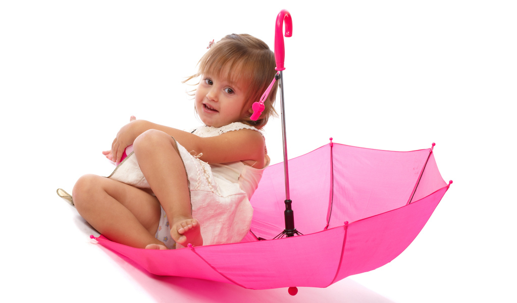 Маленькая девочка сидит в розовом зонте на белом фоне