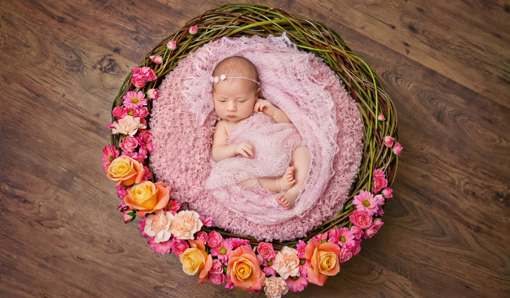 Маленькая девочка спит в корзине украшенной цветами