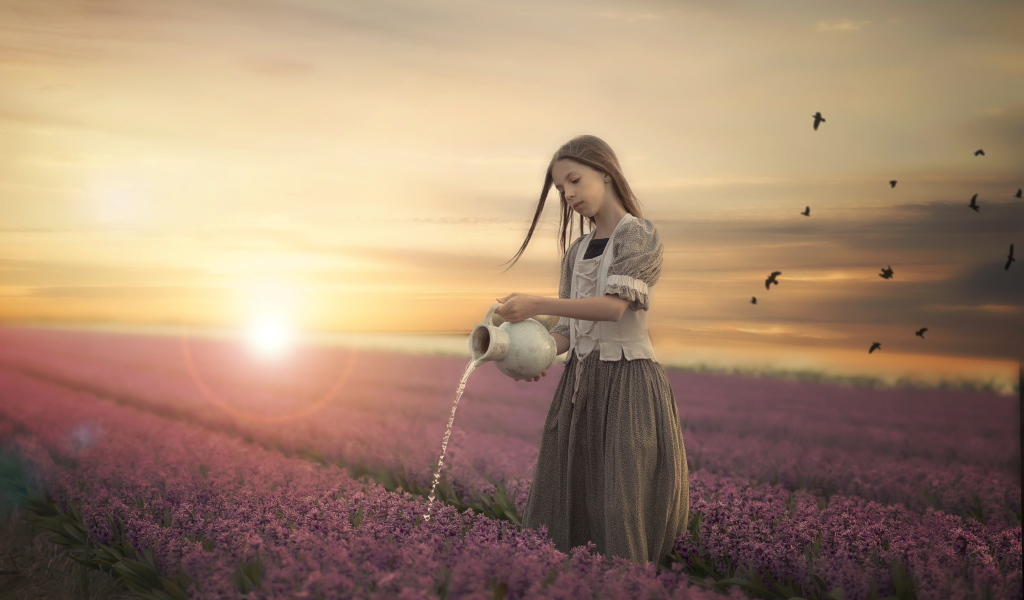 Маленькая девочка поливает цветы из кувшина в поле на закате