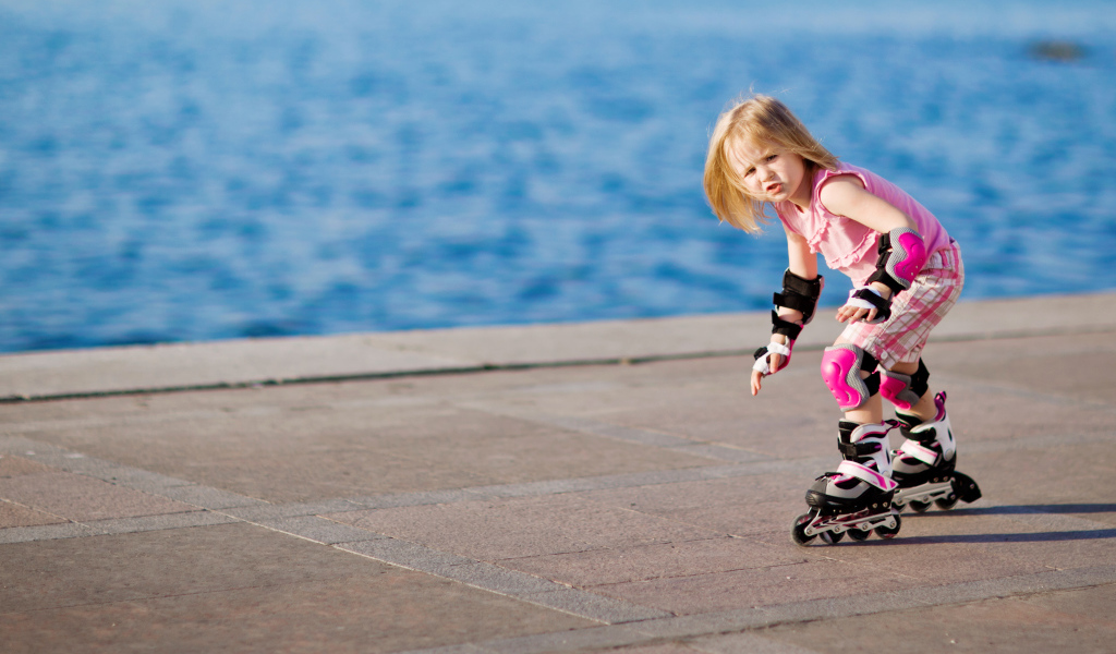 Маленькая девочка катается на роликах на побережье
